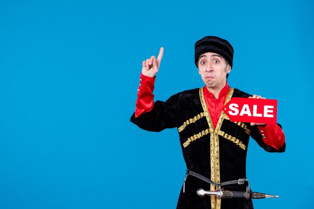 Vista superior de un joven asustado vestido tradicional que muestra un icono de venta y apunta hacia el fondo de la ola azul