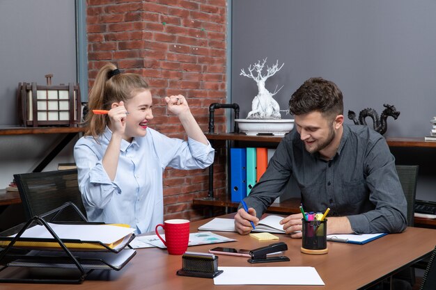 Vista superior del joven equipo de oficina sonriente, motivado y trabajador, centrado en un tema en el entorno de la oficina