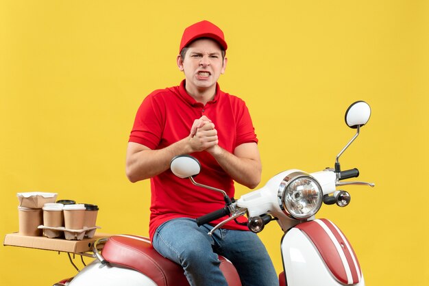 Foto gratuita vista superior del joven nervioso vestido con blusa roja y sombrero entregando pedidos sobre fondo amarillo