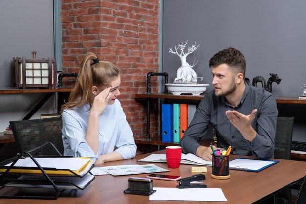 Vista superior de jóvenes compañeros de trabajo de gestión que discuten un tema importante en el entorno de oficina