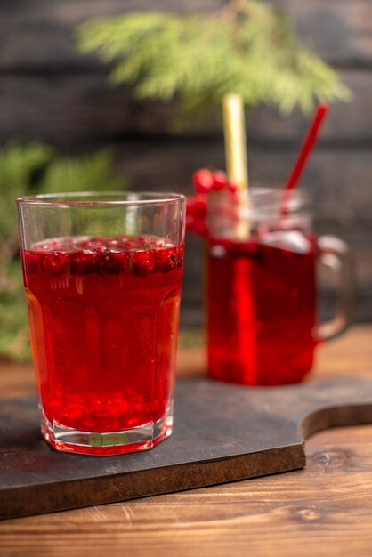 Vista superior de jugo de grosella fresca orgánica natural en una botella y un vaso servido con tubos en una tabla de cortar de madera