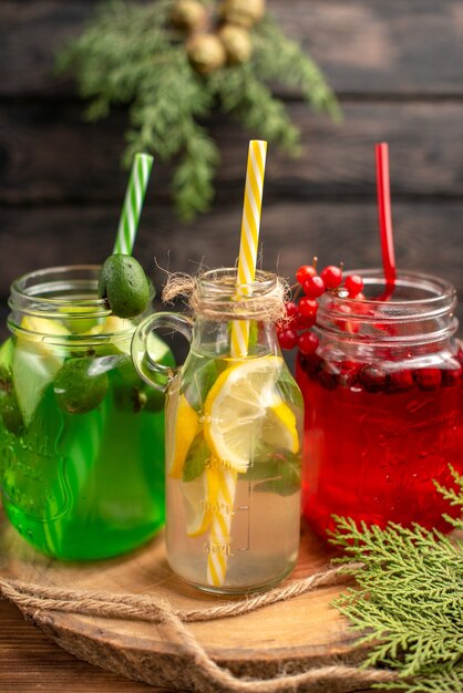 Vista superior de jugos de fuit orgánicos naturales en botellas servidas con tubos sobre una tabla de cortar de madera