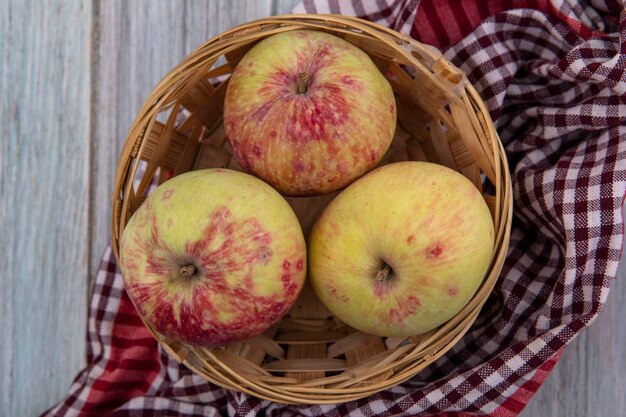 Vista superior de jugosas manzanas frescas en un balde sobre una tela marcada sobre un fondo gris