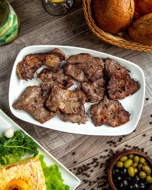 Vista superior de kebab de carne en un plato blanco sobre la mesa