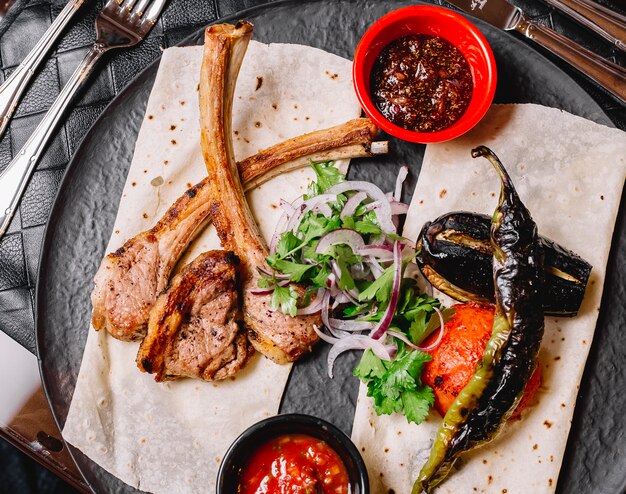 Vista superior del kebab de costillas azerbaiyano servido con verduras a la parrilla en pan plano