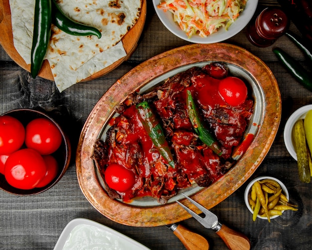 Vista superior del kebab iskender cubierto con pimiento y tomate