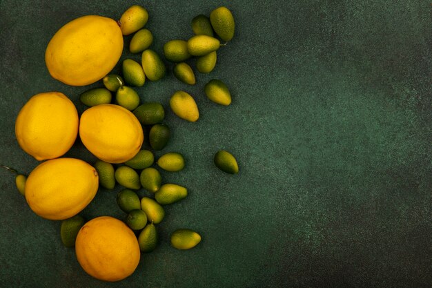 Foto gratuita vista superior de kinkans con sabor agridulce con limones aislado sobre un fondo verde con espacio de copia