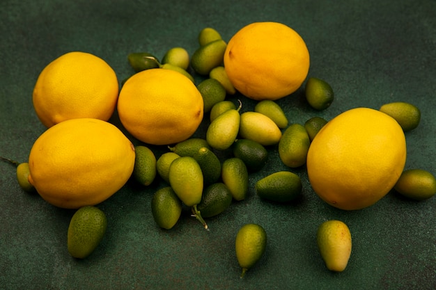 Foto gratuita vista superior de kinkans con sabor agridulce con limones aislado sobre una superficie verde