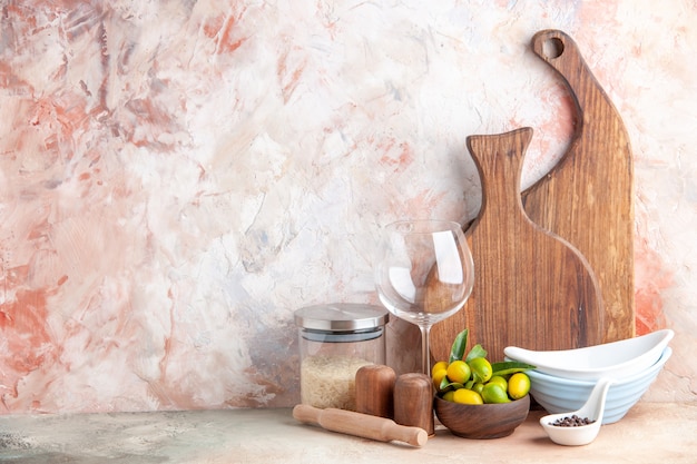 Foto gratuita vista superior de kumquats frescos ollas apiladas tablas de cortar de madera arroz cáliz de vidrio en superficie colorida