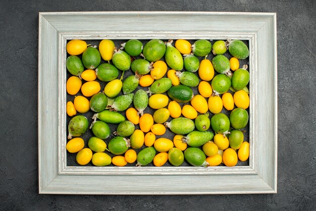 Vista superior de kumquats en marco de imagen gris sobre fondo negro