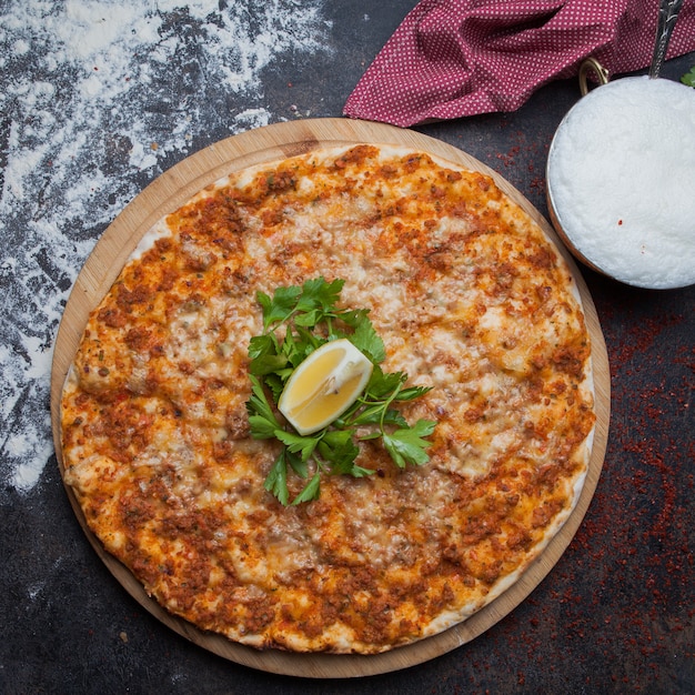 Vista superior lahmacun con perejil y limón y trapo y ayran en bandeja de comida de madera