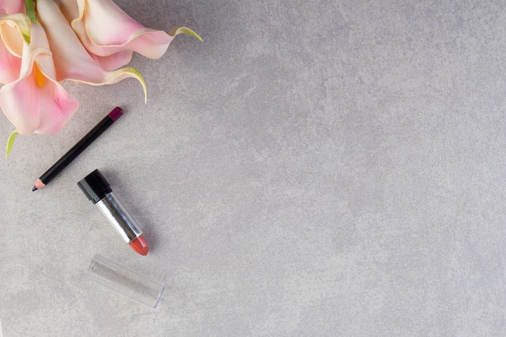 Foto gratuito vista superior de lápiz y lápiz labial sobre superficie gris