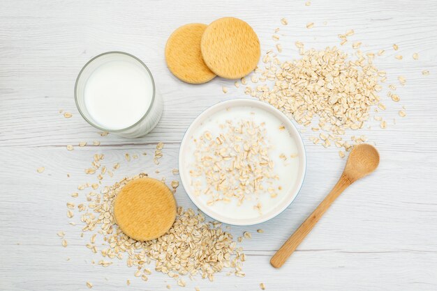 Vista superior de leche con avena junto con un vaso de leche y galletas en blanco, leche de desayuno salud láctea