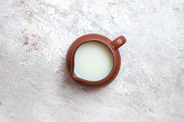 Vista superior de la leche fresca dentro de la jarra marrón sobre la superficie blanca crema de queso de productos lácteos de leche