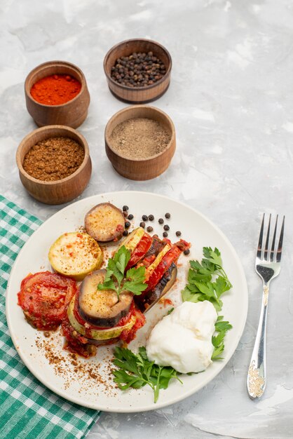 Vista superior lejana comida vegetal con verduras y condimentos en el plato de cena de comida vegetal de fondo blanco