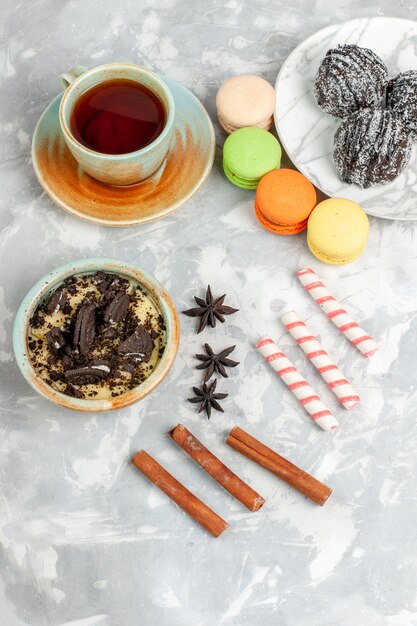 Vista superior lejana taza de té con macarrones postre y pasteles de chocolate en el escritorio blanco hornear pastel galleta azúcar pastel dulce