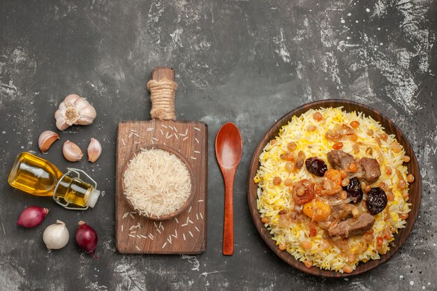 Vista superior desde lejos arroz pilaf cebolla ajo botella de aceite cuchara tazón de arroz en el tablero