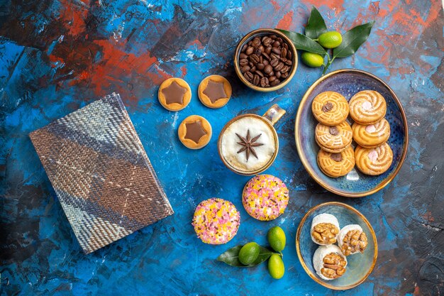 Vista superior desde lejos dulces las apetitosas galletas granos de café en un tazón de mantel de frutas cítricas