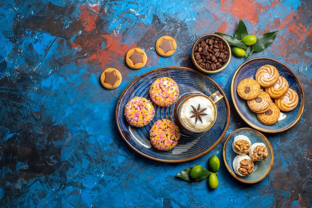 Vista superior desde lejos dulces una taza de café con galletas granos de café cítricos