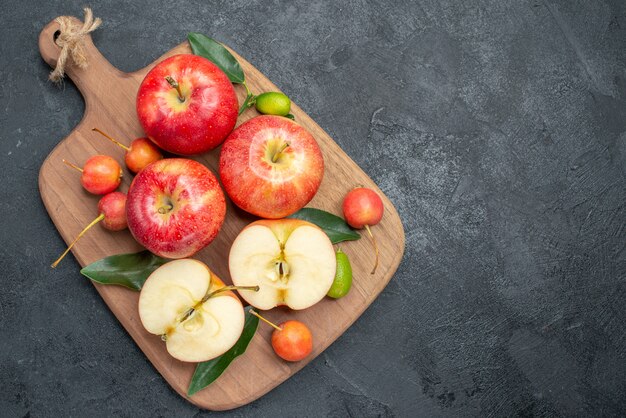 Vista superior desde lejos manzanas cerezas manzanas cítricos en la tabla de cortar