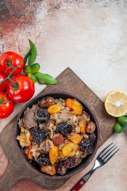 Vista superior desde lejos pilaf la tabla de cortar con tenedor pilaf tomates limón