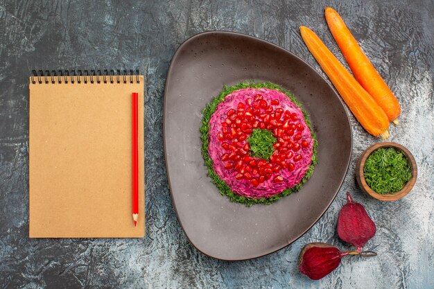 Vista superior desde lejos un plato apetitoso plato de hierbas cuaderno lápiz zanahorias remolachas