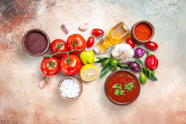 Foto gratuita vista superior desde lejos verduras especias salsas cebolla ajo limón tomates con pedicelos aceite pimienta