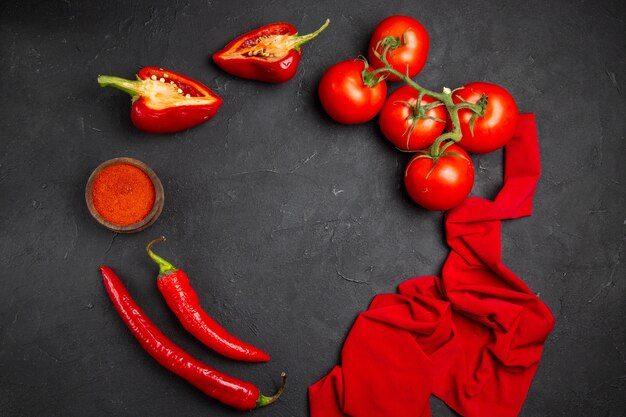 Vista superior desde lejos verduras mantel rojo especias pimientos tomates pimientos rojos