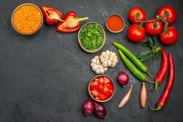 Vista superior de lentejas de verduras coloridas en un tazón junto a las verduras y especias de colores