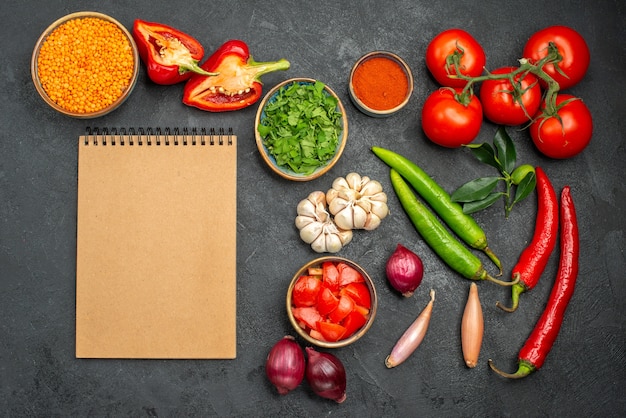 Vista superior de lentejas de verduras en un tazón junto al cuaderno de especias y verduras de colores