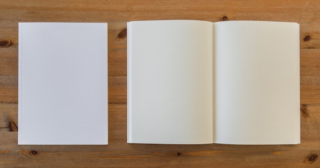 Vista superior de libro abierto en blanco junto a hojas de papel