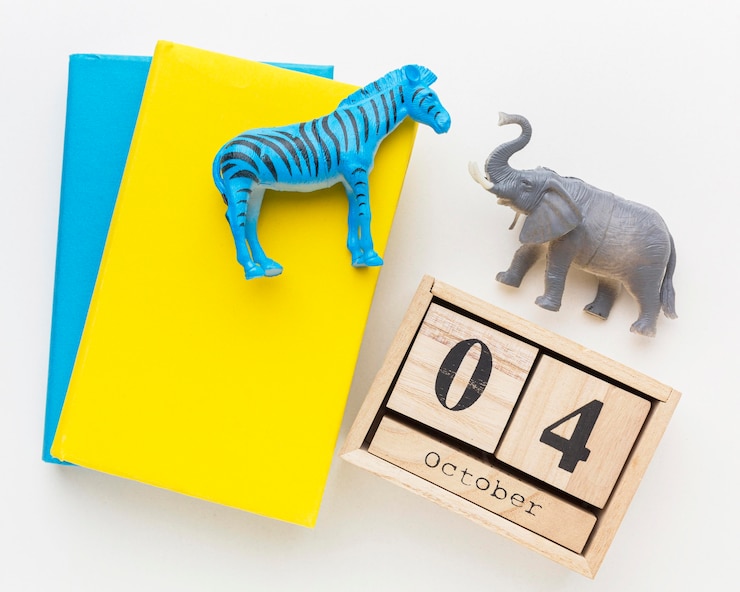 Foto gratuito vista superior del libro y calendario de madera con figuras de animales para el día de los animales