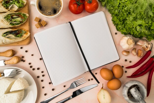 Vista superior del libro de menú vacío con ensalada y queso