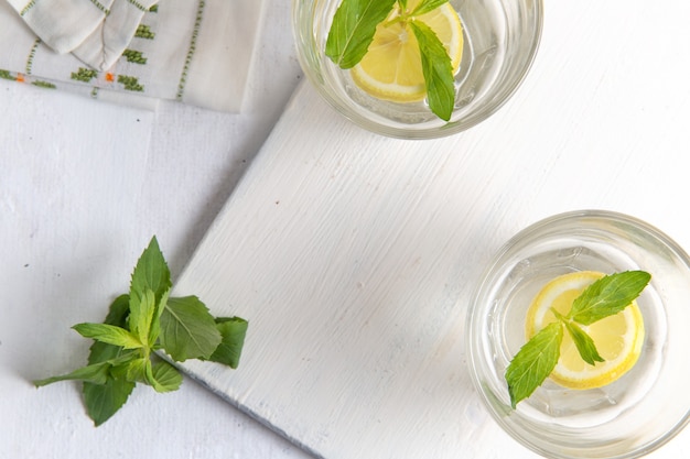 Vista superior de limonada fresca fresca con limones en rodajas dentro de vasos sobre una superficie blanca clara