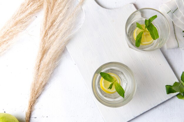 Vista superior de limonada fresca fresca con limones en rodajas dentro de vasos en la superficie blanca
