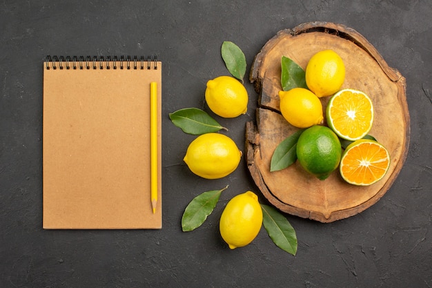 Vista superior de limones agrios frescos con hojas en la mesa oscura cítricos de lima de fruta amarilla