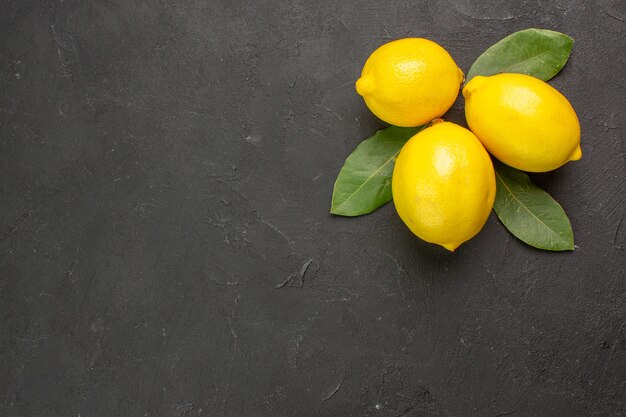 Vista superior de limones amargos frescos con hojas en la mesa oscura cítricos amarillo lima