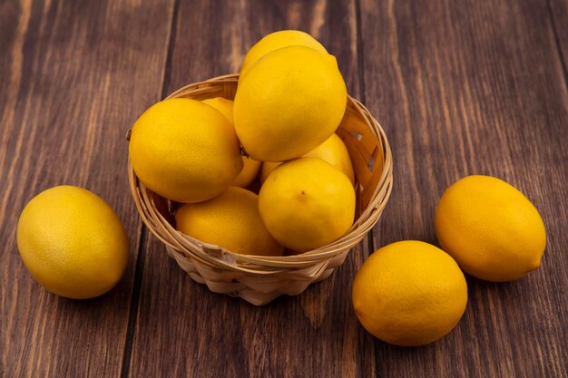 Vista superior de limones amarillos frescos en un balde con limones aislado en una pared de madera