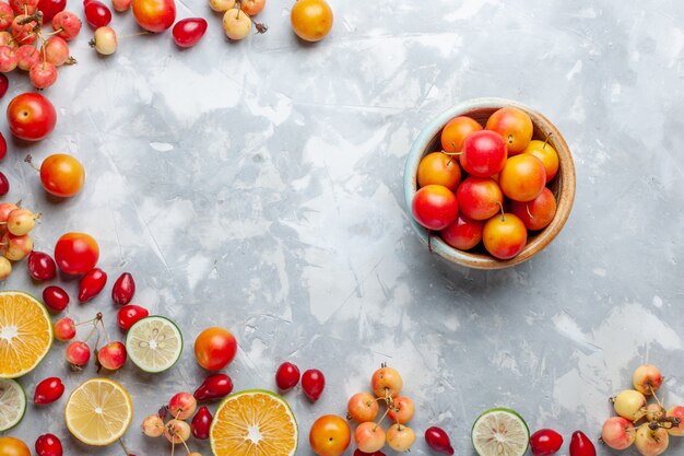 Vista superior de limones y cerezas frutas frescas con olla de ciruelas cereza en la mesa de luz fruta fresca suave madura