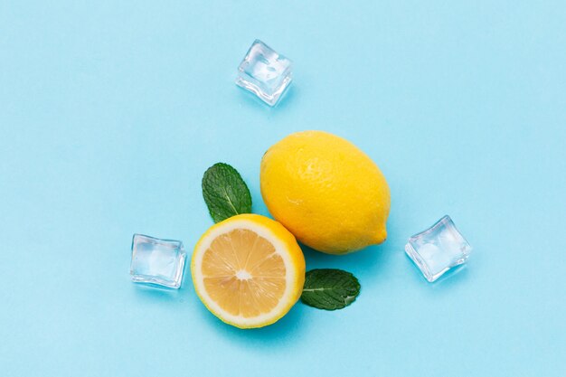 Vista superior de limones y cubitos de hielo en la superficie azul bebé