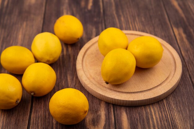 Vista superior de limones frescos aislados en una tabla de cocina de madera en una pared de madera