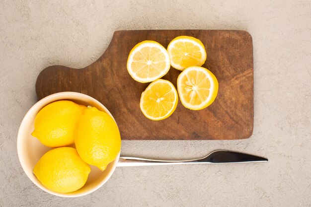 Una vista superior de limones frescos amargos maduros enteros y en rodajas cítricos suaves vitamina amarilla amarilla en el escritorio de crema