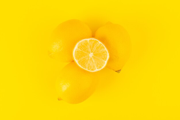 Una vista superior limones frescos amarillos frutas maduras enteras y en rodajas frescas aisladas sobre el fondo amarillo color de cítricos