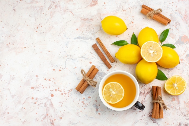 Vista superior de limones frescos cortados de limón canela en rama una taza de té de limón en la superficie aislada brillante espacio libre