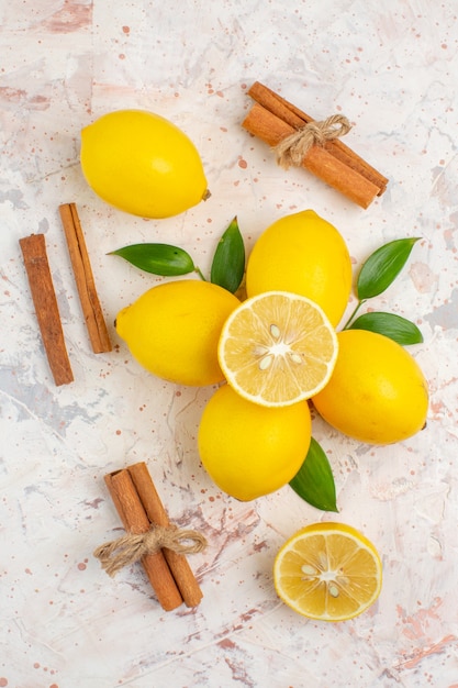 Foto gratuita vista superior de limones frescos cortados en palitos de canela y limón en una superficie aislada brillante
