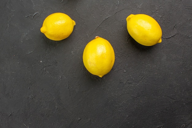 Vista superior de los limones frescos forrados en la mesa oscura cítricos limón fruta amarilla