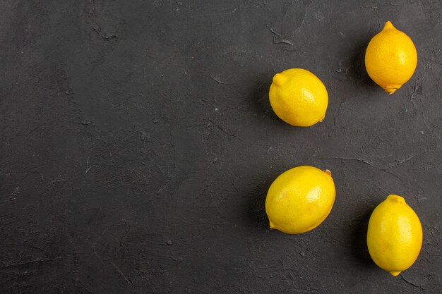 Vista superior de limones frescos forrados en una mesa oscura, fruta amarilla cítrica, espacio libre para texto