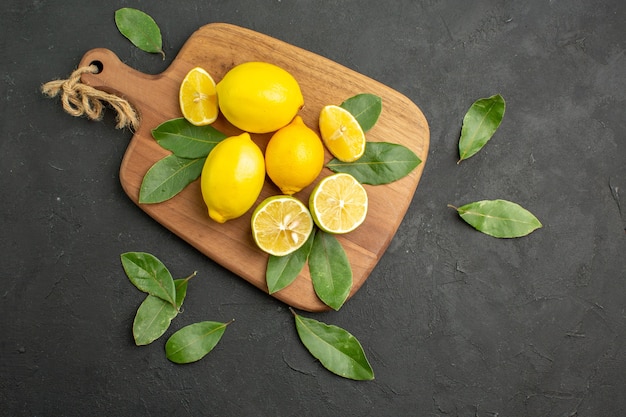 Vista superior de limones frescos frutas ácidas en lima de fruta de mesa oscura