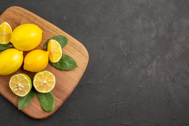 Vista superior limones frescos frutas ácidas en la mesa de color gris oscuro cítricos lima