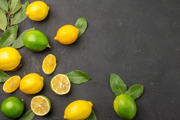 Vista superior limones frescos frutas ácidas en la mesa oscura cítricos lima